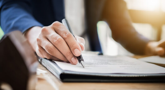 estate agent gives pen and documents agreement with customer to